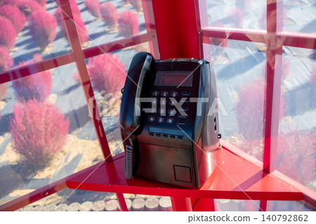 A red telephone booth and a retro public telephone. A red telephone booth and a retro public telephone. 140792862