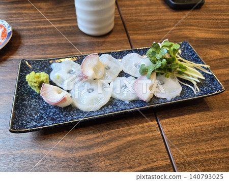 Fresh raw octopus sashimi, thinly sliced (served with wasabi and daikon sprouts), served at a Japanese restaurant. Fresh raw octopus sashimi, thinly sliced (served with wasabi and daikon sprouts), served at a Japanese restaurant. 140793025