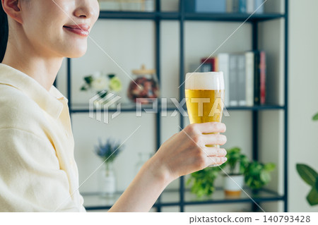 一位年輕女子在家喝啤酒時的手 一位年輕女子在家喝啤酒時的手 140793428