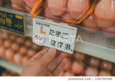 Close-up of hands operating a digital plastic device in the egg section of a supermarket. Close-up of hands operating a digital plastic device in the egg section of a supermarket. 140794366