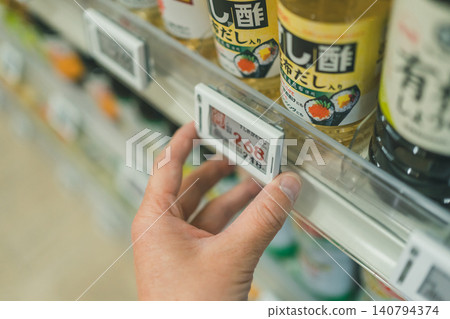 超市員工在更換醋區電子貨架標籤時的手。 超市員工在更換醋區電子貨架標籤時的手。 140794374