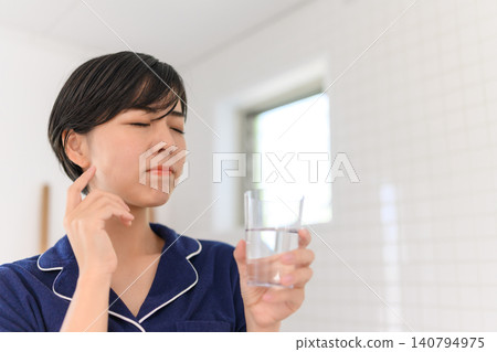 A woman winces in pain from a toothache. 140794975