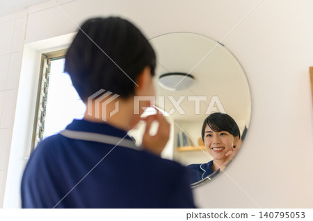 A woman checking the condition of her skin in front of a mirror 140795053