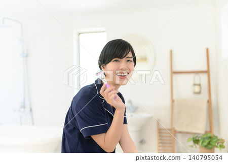 A woman smiling while holding a razor. 140795054