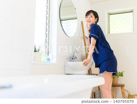 一位年輕的日本女子正在浴室洗手台邊照鏡子。 一位年輕的日本女子正在浴室洗手台邊照鏡子。 140795070
