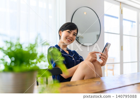 A woman's smile as she looks at her smartphone at home. A woman's smile as she looks at her smartphone at home. 140795088