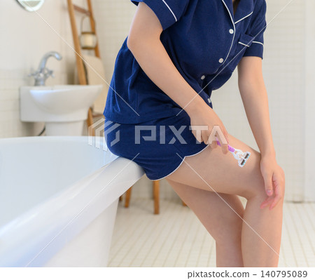A young woman shaving her legs in the bathroom. A young woman shaving her legs in the bathroom. 140795089