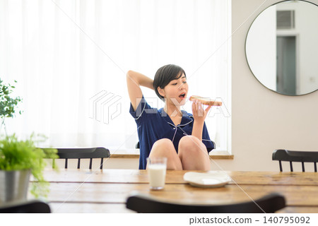A young woman eating bread at the dinner table A young woman eating bread at the dinner table 140795092