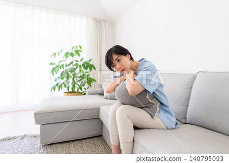 一位女子倚靠在沙發上的靠墊上,陷入沉思。 一位女子倚靠在沙發上的靠墊上,陷入沉思。 140795093