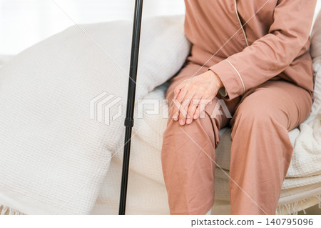 A senior woman in pajamas, complaining of knee pain as she gets out of bed (knee, knee pain) A senior woman in pajamas, complaining of knee pain as she gets out of bed (knee, knee pain) 140795096