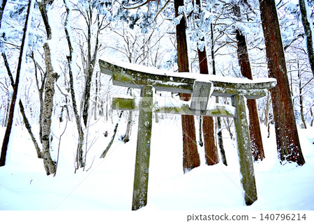 A stone torii gate and snowscape standing in a silent forest enveloped in deep snow. A stone torii gate and snowscape standing in a silent forest enveloped in deep snow. 140796214