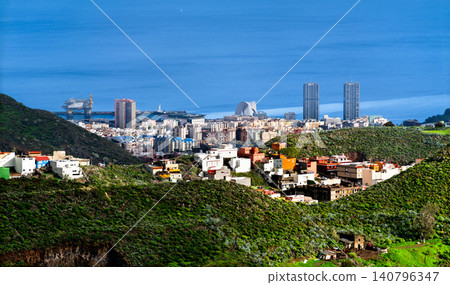 A beautiful panoramic view of Santa Cruz de Tenerife showing the city skyline, the iconic auditorium, twin towers, and the blue Atlantic Ocean from the green hills of La Laguna in Spain. A beautiful panoramic view of Santa Cruz de Tenerife showing the city skyline, the iconic auditorium, twin towers, and the blue Atlantic Ocean from the green hills of La Laguna in Spain. 140796347