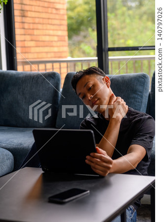 Man looking at tablet on sofa Man looking at tablet on sofa 140797026