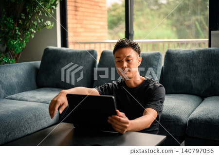 A man seeing a tablet in the living room A man seeing a tablet in the living room 140797036