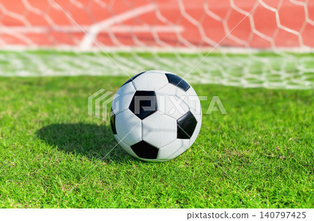 Classic Black and White Soccer Ball on Green Grass Pitch with Goal Net Background Classic Black and White Soccer Ball on Green Grass Pitch with Goal Net Background 140797425