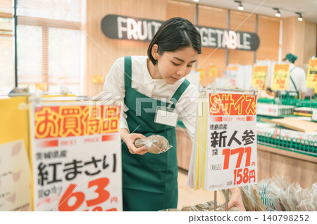 一名女員工正在超市的蔬菜區工作。 一名女員工正在超市的蔬菜區工作。 140798252