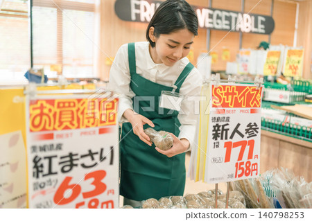 一名女店員正在超市蔬菜區整理商品。 一名女店員正在超市蔬菜區整理商品。 140798253