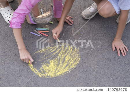 Close-up of a child's hand drawing with colored chalk on the asphalt Close-up of a child's hand drawing with colored chalk on the asphalt 140798678