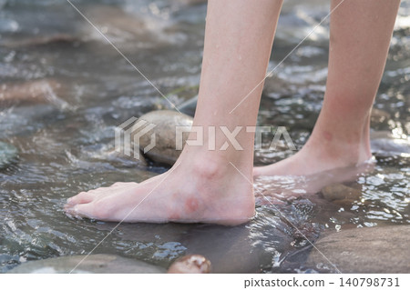 Close-up of bare feet standing in clear cold river water on smooth stones Close-up of bare feet standing in clear cold river water on smooth stones 140798731
