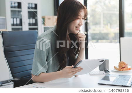Young businesswoman professional employee using pc doing online banking analysing at workplace. Asian middle-aged business woman working on laptop computer in office, taking notes. Banner, copy space Young businesswoman professional employee using pc doing online banking analysing at workplace. Asian middle-aged business woman working on laptop computer in office, taking notes. Banner, copy space 140798836