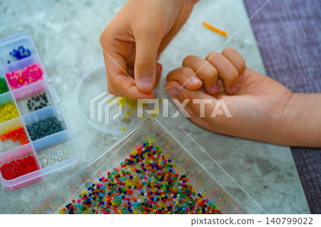 A creative girl is engaged in beadwork. Hobby and small business concept A creative girl is engaged in beadwork. Hobby and small business concept 140799022