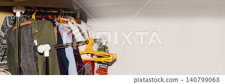 Clothes hanging on open rail wardrobe rack close up. Variety of colorful garments on hangers in walk in closet, home storage organization banner with copy space Clothes hanging on open rail wardrobe rack close up. Variety of colorful garments on hangers in walk in closet, home storage organization banner with copy space 140799068
