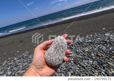 A hand holding up a stone in a tilted composition. 140799272