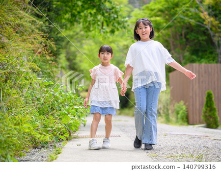 兩姊妹手牽手走在林蔭大道上。 140799316