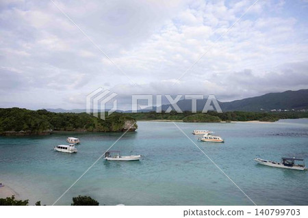 A beautiful view of the emerald green bay and the white tourist boats anchored there, seen from a hilltop. A beautiful view of the emerald green bay and the white tourist boats anchored there, seen from a hilltop. 140799703