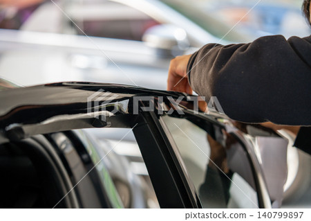 A car wrapping specialist applies a polyurethane film to the car. Detailer PPF A car wrapping specialist applies a polyurethane film to the car. Detailer PPF 140799897