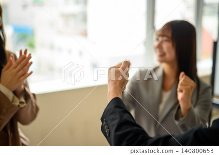 Business team celebrates by making a fist pump in the office 140800653