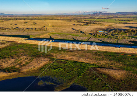 Aerial view showcasing the Lake Keepit earth embankment and surrounding rural landscape, highlighting the scale of the reservoir and the engineering features of the dam in NSW, Australia. 140800763