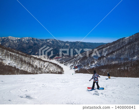 Snowboarders skiing down the steep slopes of Hakuba Cortina Ski Resort with the Northern Alps in the background (Otari Village, Nagano Prefecture). Snowboarders skiing down the steep slopes of Hakuba Cortina Ski Resort with the Northern Alps in the background (Otari Village, Nagano Prefecture). 140800841
