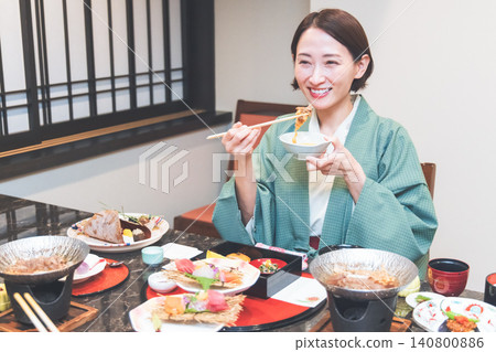 A woman eating food at a ryokan A woman eating food at a ryokan 140800886