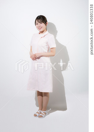美容護士、牙科保健員、牙科助理等,身穿粉紅色護士制服,面帶微笑,在牙科診所擺出導遊或接待員的姿勢。 美容護士、牙科保健員、牙科助理等,身穿粉紅色護士制服,面帶微笑,在牙科診所擺出導遊或接待員的姿勢。 140801338