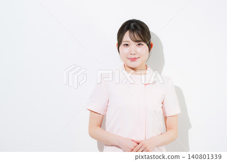 美容護士、牙科保健員、牙科助理等,身穿粉紅色護士制服,面帶微笑,在牙科診所擺出導遊或接待員的姿勢。 美容護士、牙科保健員、牙科助理等,身穿粉紅色護士制服,面帶微笑,在牙科診所擺出導遊或接待員的姿勢。 140801339