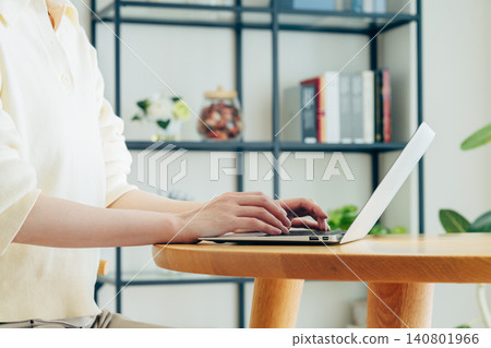 一位年輕女子在家使用電腦時的雙手 一位年輕女子在家使用電腦時的雙手 140801966