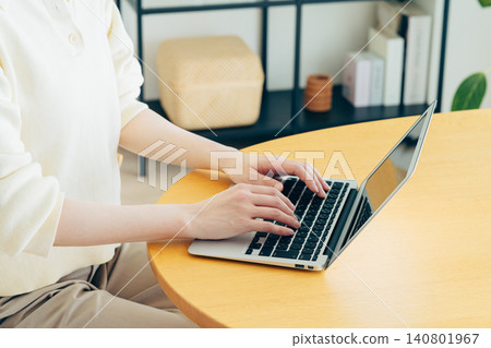 A young woman's hands as she uses her computer at home 140801967