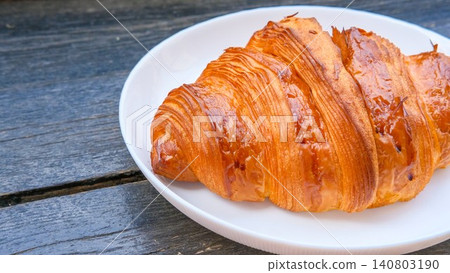 Fresh baked croissant on plate, served on wooden table in cafe or terrace. Bakery and pastry shop, morning breakfast. Taking a break, snack for lunch Fresh baked croissant on plate, served on wooden table in cafe or terrace. Bakery and pastry shop, morning breakfast. Taking a break, snack for lunch 140803190