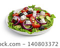 A Greek salad in a white plate is isolated in close-up on a white background. 140803372