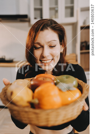 Woman preparing green smoothie in bright kitchen with fresh fruits and vegetables, healthy eating lifestyle moment in natural daylight 140803637