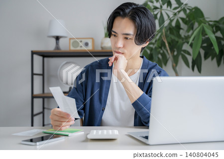 A man looking at a receipt; saving money. 140804045