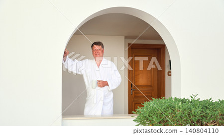 Portrait of a relaxed man in a robe holding a mug of his favorite tea 140804110