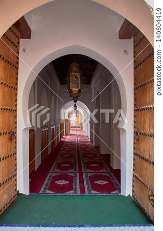 A corridor with red carpets guides the eye through the arches of the Grand Mosque of Meknes. 140804419