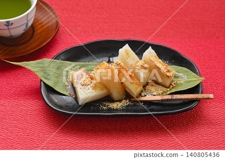 Kudzu mochi served on a bamboo leaf, topped with kinako (roasted soybean flour) and brown sugar syrup. 140805436