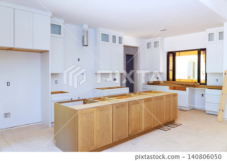 Workers are busy installing cabinets counters in kitchen under renovation, unfinished areas. Workers are busy installing cabinets counters in kitchen under renovation, unfinished areas. 140806050