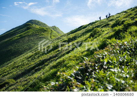 在谷川山上,登山者沿著山脊行走,周圍環繞著藍天和夏日綠意。 在谷川山上,登山者沿著山脊行走,周圍環繞著藍天和夏日綠意。 140806680