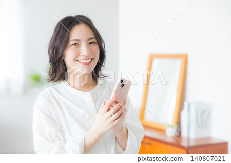 Young woman looking at her smartphone in the living room Young woman looking at her smartphone in the living room 140807021