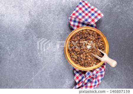 Chocolate granola in wooden bowl with scoop Chocolate granola in wooden bowl with scoop 140807139