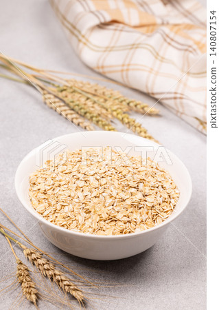 Bowl of raw oatmeal flakes with wheat ears Bowl of raw oatmeal flakes with wheat ears 140807154